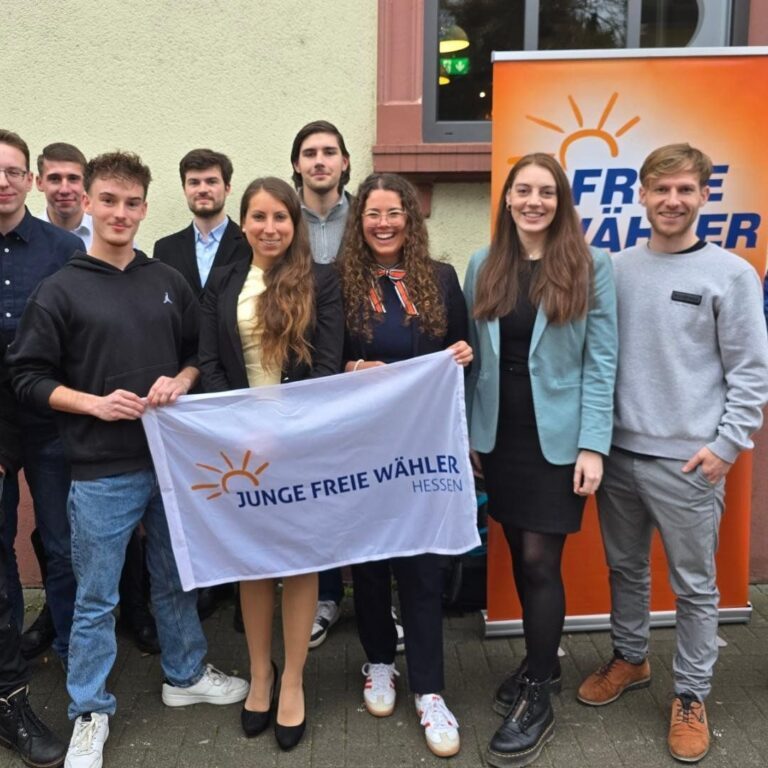 Gruppenzusammenkunft mit politischen Aktivisten, Banner der Freien Wähler im Hintergrund.